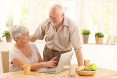 Happy senior couple with computer at home