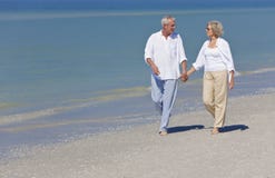 Happy Senior Couple Walking Holding Hands On Beach Stock Photo Happy Senior Couple Walking Holding Hands On Beach Stock Photo