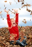 Happy Seven Year Old Girl Playing in Pile of Leaves