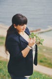 Happy smiling beautiful overweight young woman in dark blue jacket outdoors near to sea with flowers. Confident fat young woman. Happy smiling beautiful Royalty Free Stock Photography Happy smiling beautiful overweight young woman in dark blue jacket outdoors near to sea with flowers. Confident fat young woman. Happy smiling beautiful Royalty Free Stock Photography