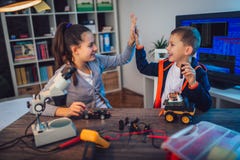 Happy smiling boy and girl constructs technical toy and make robot stock photo Happy smiling boy and girl constructs technical toy and make robot stock photo