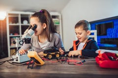 Smiling boy and girl constructs technical toy and make robot. Technical toy on table full of details royalty free stock image Smiling boy and girl constructs technical toy and make robot. Technical toy on table full of details royalty free stock image