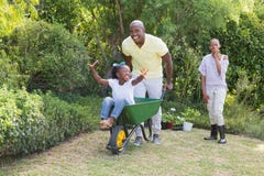 Happy smiling couple playing with wheelbarrow and their daughter royalty free stock photography Happy smiling couple playing with wheelbarrow and their daughter royalty free stock photography