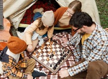 Happy Smiling Family Playing Chess Game At Campsite During Camping Trip In Nature Stock Photography