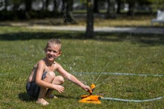 Happy Smiling Little Boy Play In Water Drops From Irrigation Hose Royalty Free Stock Photo