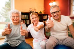 Happy smiling senior people with nurse shows finger up after success treatment stock photos Happy smiling senior people with nurse shows finger up after success treatment stock photos
