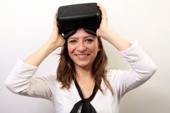 Happy, smiling woman in a white shirt, wearing Oculus Rift VR Virtual reality 3D headset, taking it off or putting it on stock image Happy, smiling woman in a white shirt, wearing Oculus Rift VR Virtual reality 3D headset, taking it off or putting it on stock image