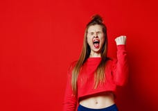 Happy successful young woman with raised hands shouting and celebrating success over red background stock photo Happy successful young woman with raised hands shouting and celebrating success over red background stock photo