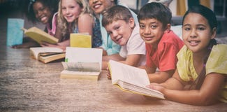Happy teacher with children lying down while reading books stock photos Happy teacher with children lying down while reading books stock photos