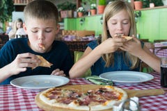 Happy teenagers eating pizza in a cafe. Friends or siblings having fun in restaurant royalty free stock images Happy teenagers eating pizza in a cafe. Friends or siblings having fun in restaurant royalty free stock images