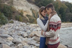 Happy thoughtful couple standing on a rock beach near sea hugging each other in cold foggy cloudy autumn weather. Copy space royalty free stock photo Happy thoughtful couple standing on a rock beach near sea hugging each other in cold foggy cloudy autumn weather. Copy space royalty free stock photo