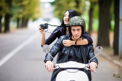 Happy tourist young couple on scooter ride in new city. Woman making photo on camera while riding outdoors royalty free stock photography Happy tourist young couple on scooter ride in new city. Woman making photo on camera while riding outdoors royalty free stock photography