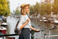 Happy traveler girl enjoying Amsterdam city. Smiling woman looking to the side on Amsterdam canal, Netherlands, Europe royalty free stock photo Happy traveler girl enjoying Amsterdam city. Smiling woman looking to the side on Amsterdam canal, Netherlands, Europe royalty free stock photo