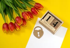 Happy Valentine`s Day concept. Bouquet of red button tulips, wooden calendar with 14 february, heart and white sheet of paper on royalty free stock photography Happy Valentine`s Day concept. Bouquet of red button tulips, wooden calendar with 14 february, heart and white sheet of paper on royalty free stock photography