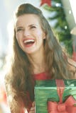 Happy woman with green Christmas gift near Christmas tree stock images Happy woman with green Christmas gift near Christmas tree stock images