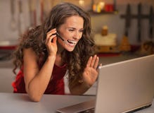Happy woman having video chat on laptop in kitchen stock image Happy woman having video chat on laptop in kitchen stock image