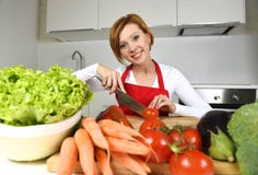Happy woman at home kitchen preparing vegetable salad with lettuce carrots and slicing tomato Stock Photo Happy woman at home kitchen preparing vegetable salad with lettuce carrots and slicing tomato Stock Photo