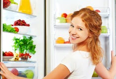 Happy woman and open refrigerator with fruits, vegetables and he stock images Happy woman and open refrigerator with fruits, vegetables and he stock images