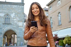 Happy woman smiling and walking in the street using a new app on the smartphone stock photography Happy woman smiling and walking in the street using a new app on the smartphone stock photography