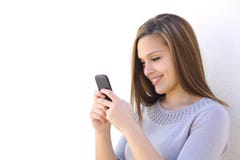 Happy woman texting on a smartphone. Looking at phone on a white wall Happy woman texting on a smartphone. Looking at phone on a white wall