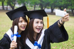 happy women in graduation gowns taking picture with cell pho royalty free stock images happy women in graduation gowns taking picture with cell pho royalty free stock images