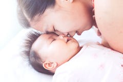 Happy young asian mother kissing her newborn baby girl with love stock images Happy young asian mother kissing her newborn baby girl with love stock images