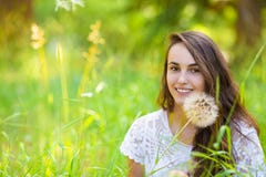 Happy young beautiful woman sitting on grass with dandelion flow Royalty Free Stock Photography Happy young beautiful woman sitting on grass with dandelion flow Royalty Free Stock Photography
