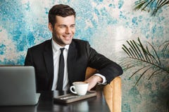 Happy young businessman sitting in cafe using laptop computer stock photo Happy young businessman sitting in cafe using laptop computer stock photo