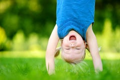 Happy young child playing head over heels on green grass stock photos Happy young child playing head over heels on green grass stock photos