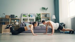 Happy young couple girl and guy doing pushups and clapping hands in apartment stock video Happy young couple girl and guy doing pushups and clapping hands in apartment stock video