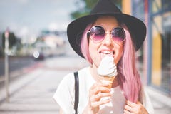 Happy young hipster woman with long pink hair, hat and sunglasses eating ice cream outdoors royalty free stock images Happy young hipster woman with long pink hair, hat and sunglasses eating ice cream outdoors royalty free stock images