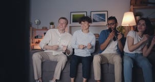 Happy young people singing and dancing watching TV at home at night stock video footage Happy young people singing and dancing watching TV at home at night stock video footage