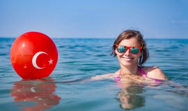Happy young woman bathing in blue sea water and holds balloon with turkish flag. Resorts in Turkey stock image Happy young woman bathing in blue sea water and holds balloon with turkish flag. Resorts in Turkey stock image
