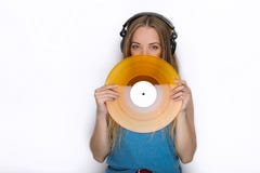 Happy young woman in big black professional dj headphones holding trendy yellow colorful vinyl record posing against white studio Stock Images Happy young woman in big black professional dj headphones holding trendy yellow colorful vinyl record posing against white studio Stock Images