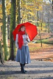 The happy young woman costs with a red umbrella in the autumn park stock photos The happy young woman costs with a red umbrella in the autumn park stock photos