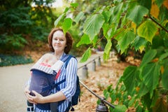 Happy young woman with her baby in carrier stock photography Happy young woman with her baby in carrier stock photography