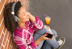 Happy young woman sitting on ground listening to music stock photos Happy young woman sitting on ground listening to music stock photos