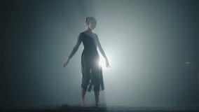 Hard-working graceful ballerina dancing in ballet shoes and black dress in the studio in spotlight on a black background stock footage Hard-working graceful ballerina dancing in ballet shoes and black dress in the studio in spotlight on a black background stock footage