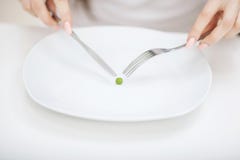 Harte Diät - verbotenes Essen Mädchen hält eine Platte und versucht, eine Erbse zu setzen lizenzfreie stockfotos Harte Diät - verbotenes Essen Mädchen hält eine Platte und versucht, eine Erbse zu setzen lizenzfreie stockfotos