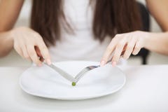Harte Diät - verbotenes Essen Mädchen hält eine Platte und versucht, eine Erbse zu setzen stockbilder Harte Diät - verbotenes Essen Mädchen hält eine Platte und versucht, eine Erbse zu setzen stockbilder