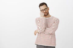 Hate waiting in queues. Portrait of annoyed tired handsome guy with bristle in black eyewear, leaning face on hand and stock images Hate waiting in queues. Portrait of annoyed tired handsome guy with bristle in black eyewear, leaning face on hand and stock images