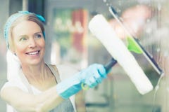 Haushälterin wischt Fenster ab lizenzfreie stockbilder Haushälterin wischt Fenster ab lizenzfreie stockbilder
