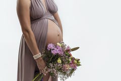 Havandeskap Utsatt buk och händer av en gravid kvinna Bukett av blommor fotografering för bildbyråer Havandeskap Utsatt buk och händer av en gravid kvinna Bukett av blommor fotografering för bildbyråer