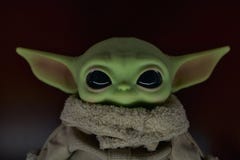April, 2021: Head of baby Grogu, baby Yoda close-up. Realistic toy. Dark background