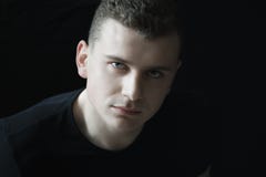 Headshot des überzeugten jungen Mannes, der Kamera in der zurückhaltenden Beleuchtung betrachtet stockfoto Headshot des überzeugten jungen Mannes, der Kamera in der zurückhaltenden Beleuchtung betrachtet stockfoto