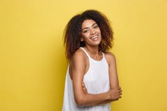 Headshot portrait of beautiful attractive African American woman posting crossed arms with happy smiling. Yellow studio Stock Photos Headshot portrait of beautiful attractive African American woman posting crossed arms with happy smiling. Yellow studio Stock Photos