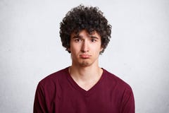 Headshot of upset attractive male curves lower lip, being dissatisfied with negative news, being sad and disappointed, poses again royalty free stock images Headshot of upset attractive male curves lower lip, being dissatisfied with negative news, being sad and disappointed, poses again royalty free stock images