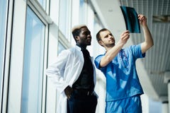 Healthcare, medical and radiology concept - two mixed race doctors looking at x-ray in modern hospital royalty free stock image Healthcare, medical and radiology concept - two mixed race doctors looking at x-ray in modern hospital royalty free stock image