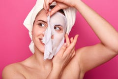 Healthy dreamy young lovely woman takes off cosmetic mask from face, has broad smile, focused aside, enjoys facial treatments, stock image Healthy dreamy young lovely woman takes off cosmetic mask from face, has broad smile, focused aside, enjoys facial treatments, stock image
