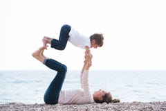 Healthy family playful pretty mother and child making exercises on autumn beach stock image Healthy family playful pretty mother and child making exercises on autumn beach stock image